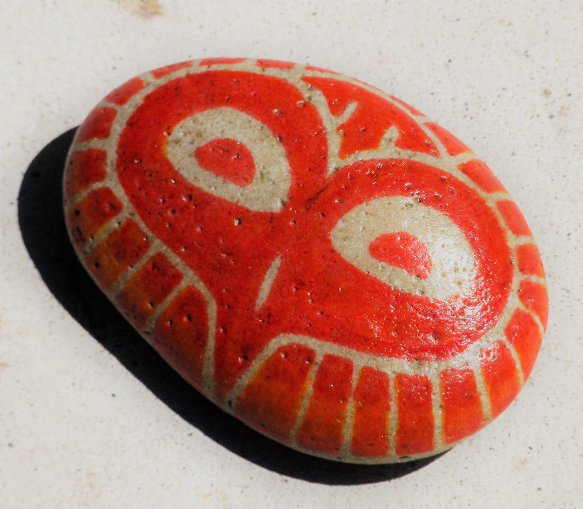 Painted stone by Lone Peep: red stone with a cream swirl pattern.