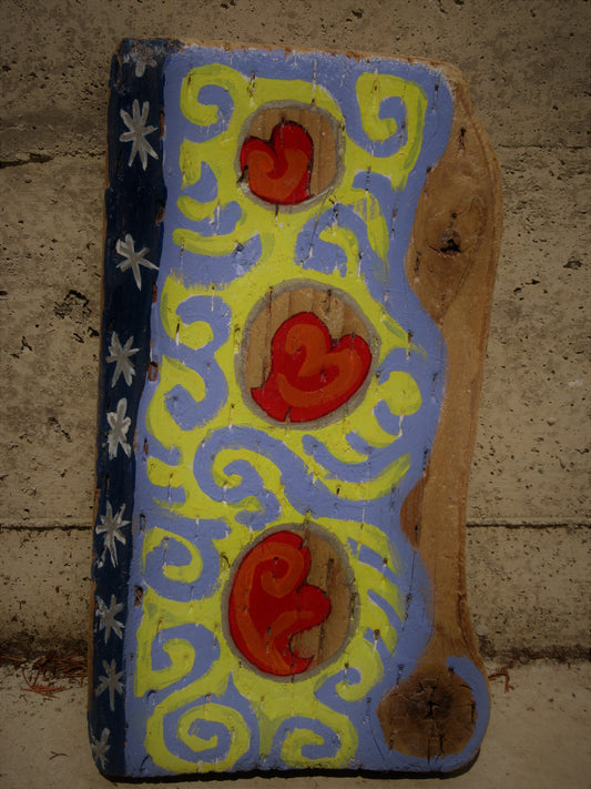 Folk art hearts painted on a wood plank by Lone Peep: red hearts with yellow and blue swirls and a star border.
