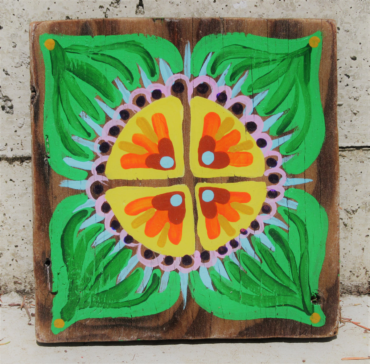Folk art flower painted on a dark wood board by Lone Peep: yellow-orange bloom with green leaves and pink dotted border.